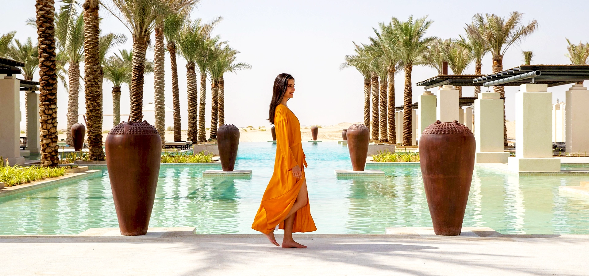 It’s Time To Travel UAE | WPJ Travel 6 Woman in an elegant orange dress walking by a luxury poolside in Dubai resort
