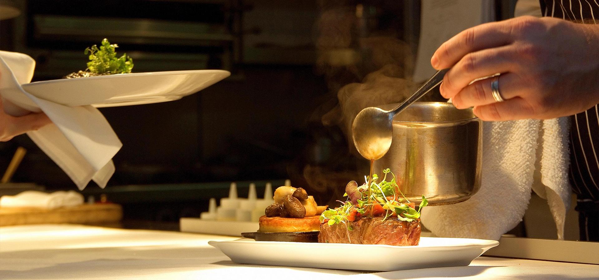 Dubai Delights | WPJ Travel 3 Close up of a chef pouring sauce over gourmet dishes at a fine dining restaurant in Dubai