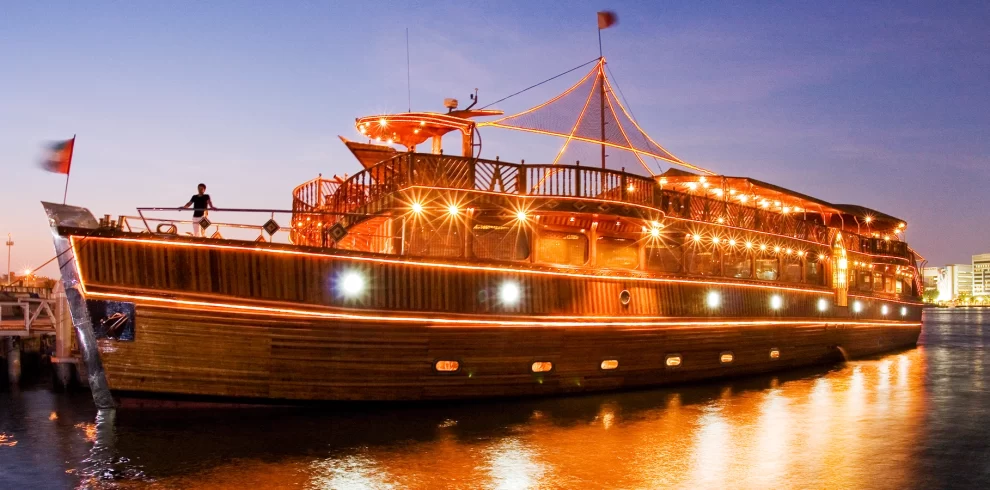 Dhow Cruise Dinner – Dubai Marina | WPJ Travel | WPJ Travel 5 Guests dining aboard a traditional dhow during a night cruise in Dubai Marina.